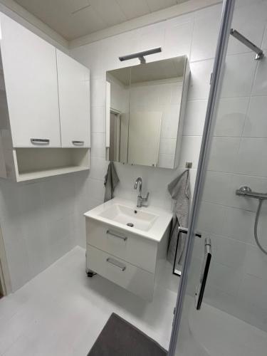 a white bathroom with a sink and a mirror at Modernes 4er Apartment in Skilift-Nähe in Zell am See