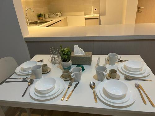 a table with white plates and silverware on it at Next to Yas Island's Gems - canal+pool view in Abu Dhabi