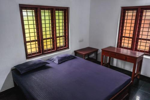 a bedroom with a bed and a desk and two windows at Secret Paradise in Varkala