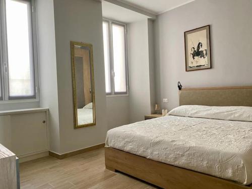 Schlafzimmer mit einem Bett, einem Spiegel und Fenstern in der Unterkunft Appartamento centralissimo in Piazza Bresca in Sanremo