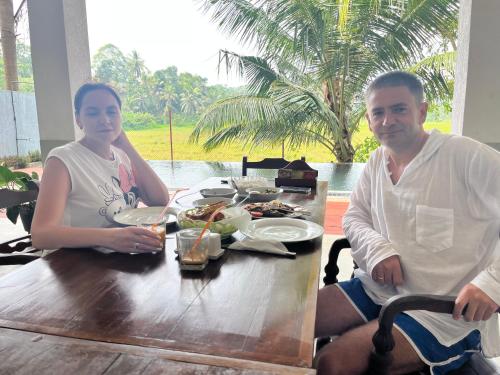 a man and woman sitting at a table with food at Green Edge Villa in Hikkaduwa