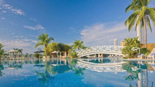 a bridge over a pool with palm trees and a building at Intercontinental Miramar Panama by IHG in Panama City
