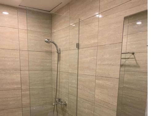 y baño con ducha y puerta de cristal. en Nine Hotel, en Palembang