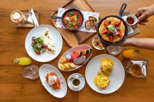 een houten tafel met borden met eten erop bij OUTRIGGER Surin Beach Resort in Surin Beach