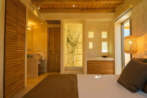 een slaapkamer met een bed en een badkamer met een wastafel bij Meli Suites Isle - Adults Only in Skala Potamias