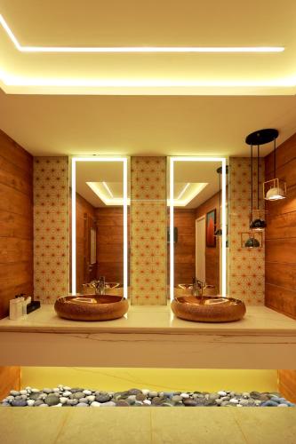 a bathroom with three sinks and two mirrors at Wooden ECR Sea Resort in Puducherry