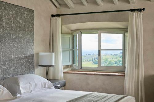 a bedroom with a bed and a large window at COMO Castello Del Nero in Tavarnelle in Val di Pesa