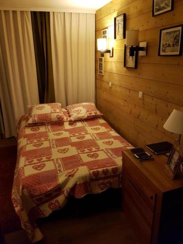 une chambre avec un lit et un mur en bois dans l'établissement Les temples du soleil, à Val Thorens