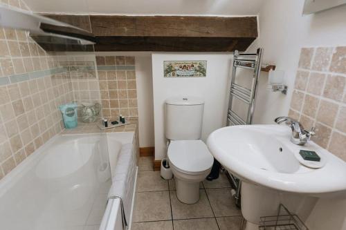 La salle de bains est pourvue de toilettes, d'un lavabo et d'une baignoire. dans l'établissement Fryers Cottage - Beautiful 2 bedroom Town & Country Cottage on edge of Peak District, à Wirksworth