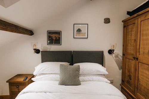 Schlafzimmer mit einem Bett mit weißer Bettwäsche und einem Holzschrank in der Unterkunft Fryers Cottage - Beautiful 2 bedroom Town & Country Cottage on edge of Peak District in Wirksworth