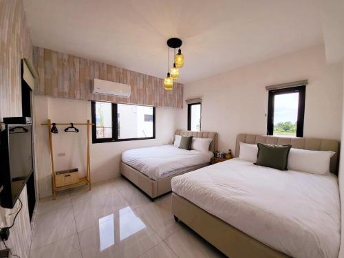 a bedroom with two beds and a tv and windows at Tipsy Snail in Sanxing