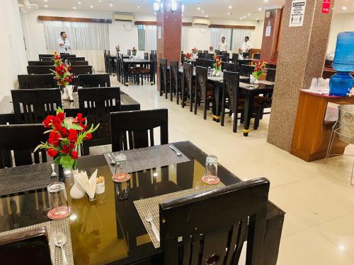 a restaurant with black tables and chairs and people in the background at Bodhgaya Regency Hotel in Bodh Gaya