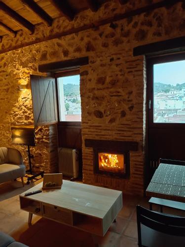 a living room with a table and a fireplace at Balcón de la Moreria con alberca in Constantina