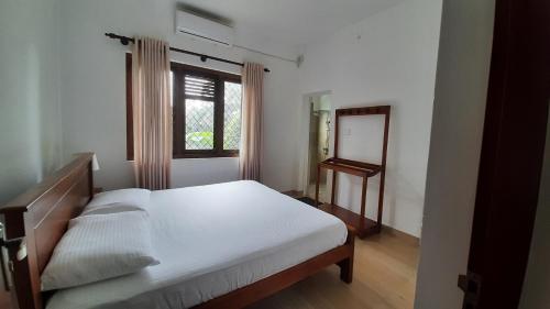 1 dormitorio con cama, espejo y ventana en Blue Ridge Homestay, en Kandy