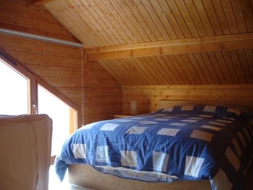 Bett in einer Hütte mit Holzdecke in der Unterkunft Grand Valtin : chalet écolo 4 étoiles 14 personnes in Ban-sur-Meurthe-Clefcy