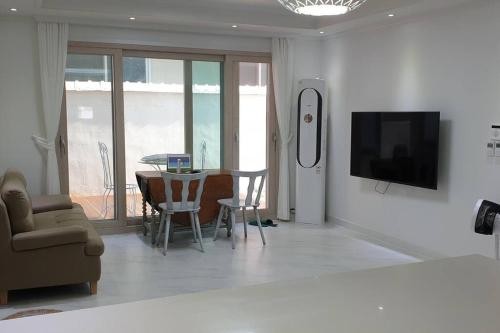 a living room with a television and a table with chairs at Gyeongju Sugi's Guesthouse in Gyeongju