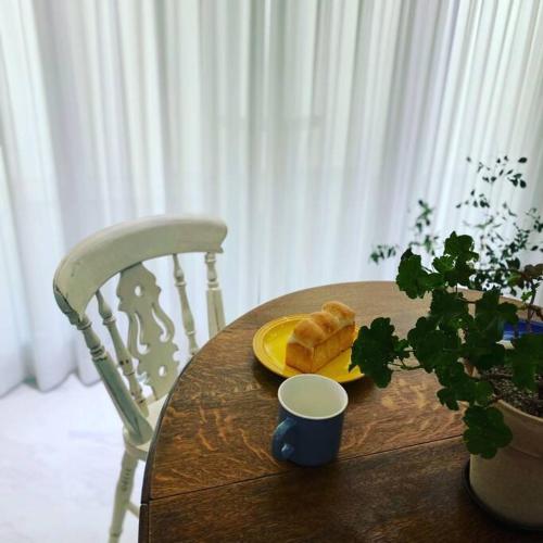 a table with a plate of bread and a cup at Gyeongju Sugi's Guesthouse in Gyeongju