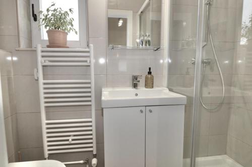 La salle de bains blanche est pourvue d'un lavabo et d'une douche. dans l'établissement Studio City, à Ljubljana