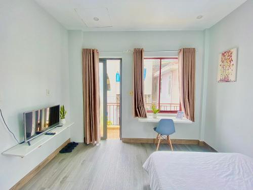 sypialnia z łóżkiem, telewizorem i oknami w obiekcie Tùng Homestay w mieście Hue