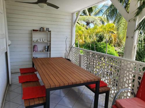porche con mesa de madera y sillas en el balcón en Appart Cocotiers, en La Saline-Les-Bains