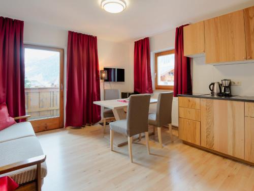 eine Küche und ein Esszimmer mit einem Tisch und roten Vorhängen in der Unterkunft Alpensport Appartement Stubai - Tannenheim in Neustift im Stubaital
