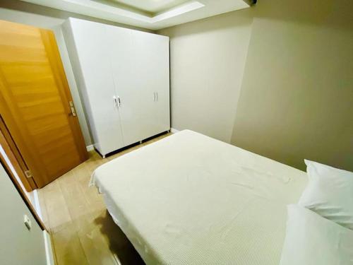 um pequeno quarto com uma cama branca e uma porta em Atasuit12 em Istambul