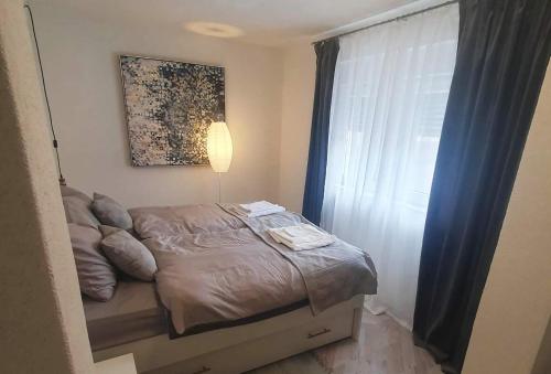 a small bedroom with a bed and a window at Apartman Incerum in Požega