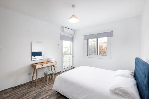 a white bedroom with a bed and a desk at Happy Stay Apartment - Halefka Court in Larnaka