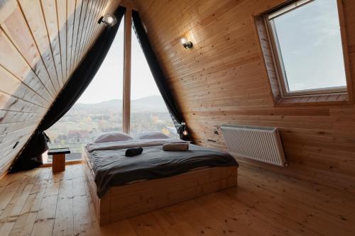 a bedroom with a bed in a wooden room with windows at Cabana Vlad Maramureș in Deseşti