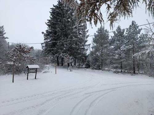 a snow covered road with a sign and trees at Rykowisko - domki całoroczne nad jeziorem i rzeką in Szczecinek