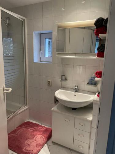 a white bathroom with a sink and a shower at Ferienhaus Weniger in Bad Saarow