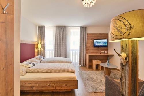 a bedroom with a bed and a desk and a television at Haus Flexen in Stuben am Arlberg