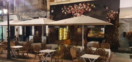 アリカンテにあるApartamentos Plazaの建物の前にあるレストラン(テーブルと傘付)