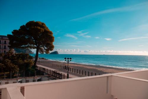 Blick auf einen Strand mit einem Baum und das Meer in der Unterkunft Hotel Ligure in Spotorno