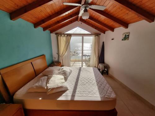 una camera con letto, ventilatore a soffitto e finestra di Harbour House a Paul do Mar