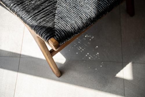a wooden chair with a black rug on a tiled floor at ZeusCave in Georgioupolis