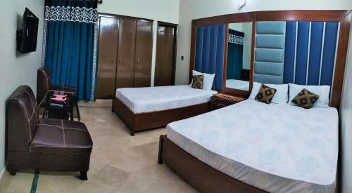 um quarto de hotel com duas camas e uma cadeira em SUBHAN PALACE Near Lasania Restaurant & Millennium Mall em Carachi