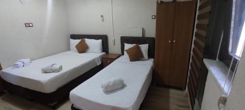 two beds in a small room with white sheets at Biter Hotel in Istanbul