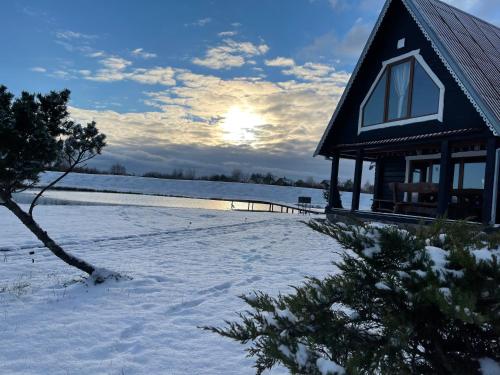 a cabin in the snow with the sun in the background at Sodyba Anykščių raj. in Anykščiai