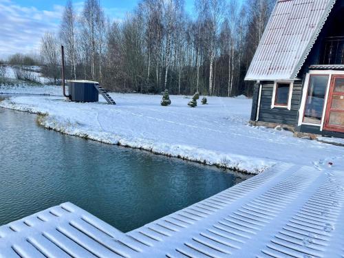 a body of water in front of a house with snow at Sodyba Anykščių raj. in Anykščiai