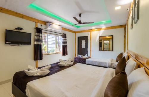 a room with two beds and a flat screen tv at Saga Resort in Mahabaleshwar