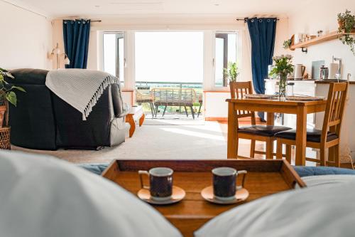 a living room with two coffee cups on a table at Spacious Sea-View Apt. Overlooking St Ives Bay in Gwithian
