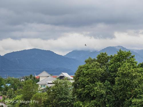 a bird flying over houses and trees with mountains in the background at Pat Holiday Home in Cha Am