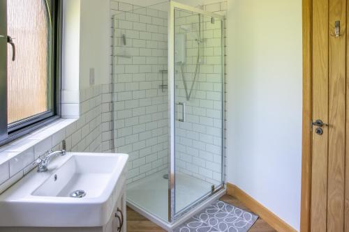 a bathroom with a glass shower and a sink at Kinlochlaich Tree House in Appin