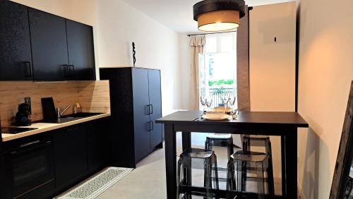 eine Küche mit schwarzen Schränken und einem Tisch mit Barhockern in der Unterkunft Grand Studio Luxe in Sète
