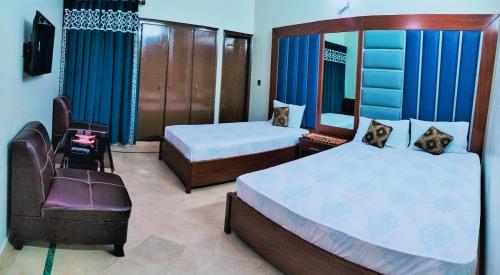 een slaapkamer met 2 bedden en een stoel bij GULSHAN E IQBAL Guest House Near Mallinum Mall & Agha Khan hospital in Karachi