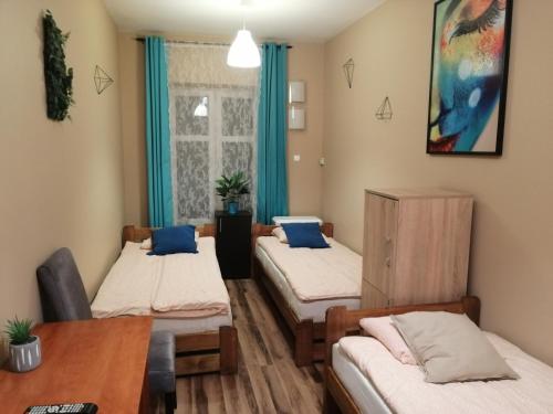 Zimmer mit 3 Betten und einem Tisch in der Unterkunft Hostel Gliwice Centrum in Gliwice