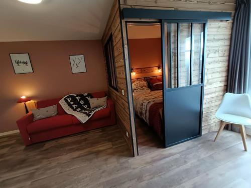 sypialnia z łóżkiem i czerwoną kanapą w obiekcie Fleurs des Alpes w mieście Les Déserts