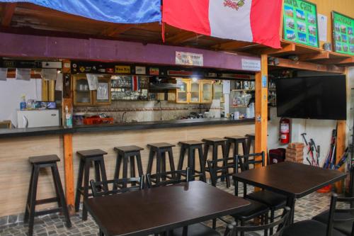 eine Bar mit Holztischen und -stühlen sowie einem TV in der Unterkunft Andes Hostel in Huaraz