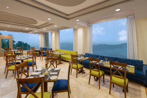 a restaurant with tables and chairs and large windows at Fortune Park Kufri, Shimla - Member ITC Hotels' Group in Shimla